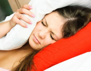 beautiful young woman suffering from insomnia and covering her head with a pillow